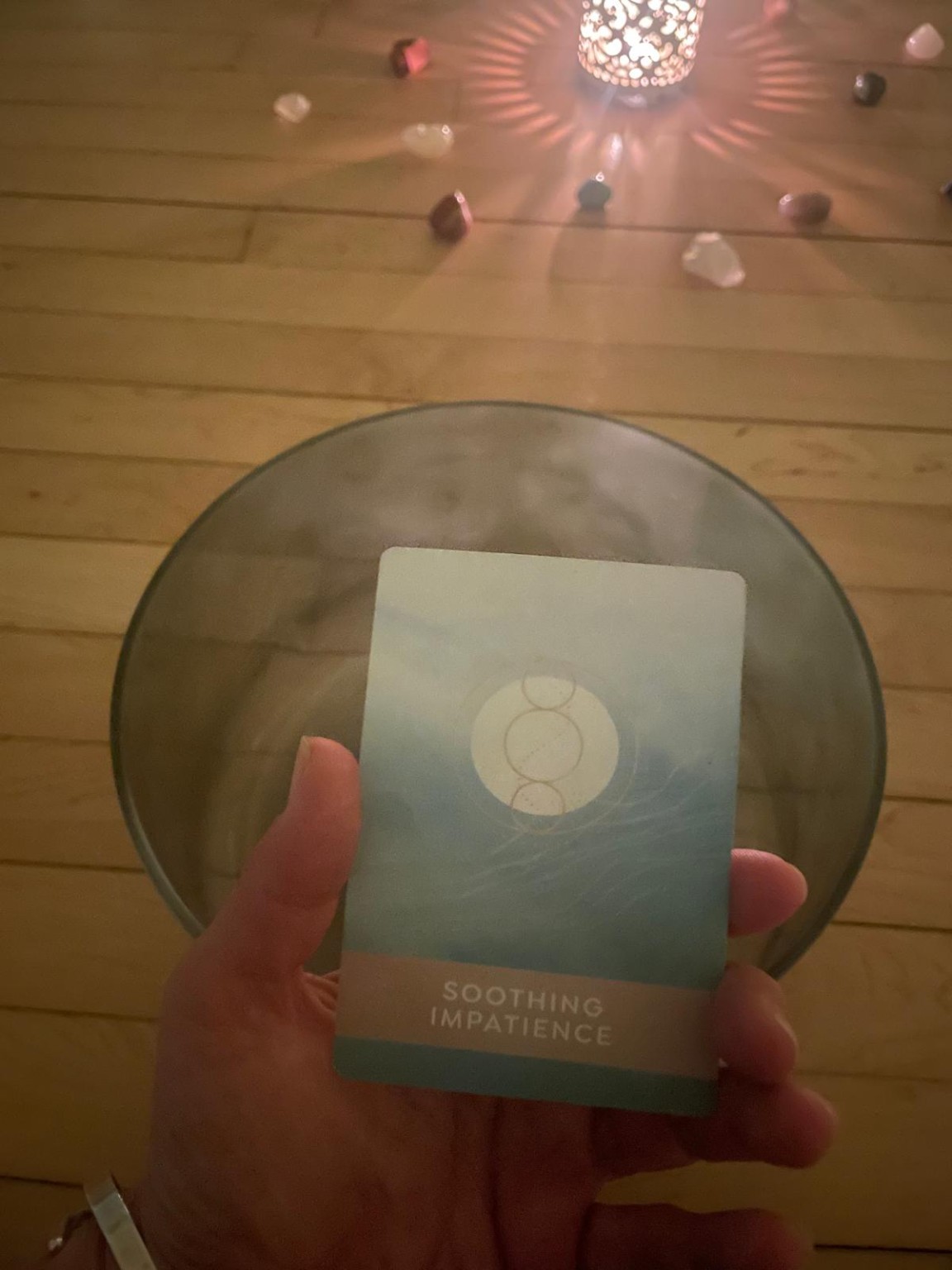 A reflection card held beside a sound bowl and candlelight